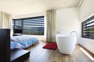 Interno di una camera da letto di design con grata a scomparsa: la vista sul paesaggio resta libera