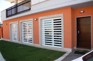 Casa color arancio con portico e grate a scomparsa bianche chiuse