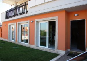 Portico di casa color arancio con grate a scomparsa bianche