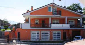 Villa color arancio con grate a scomparsa bianche viste dalla strada